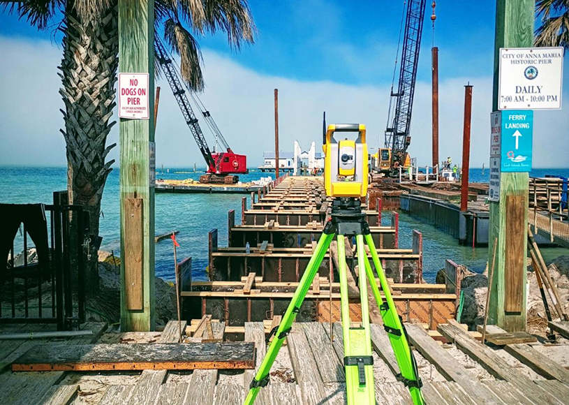 Construction site with surveying equipment by water.